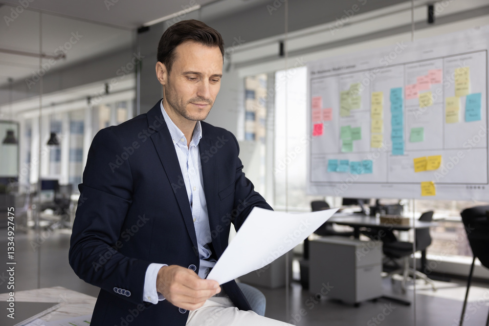 Focused Latin business executive man reading paper legal document, formal letter in office space alone, analyzing financial sales report, statistic data, doing paperwork, making decision Focused Latin business executive man reading paper legal document, formal letter in office space alone, analyzing financial sales report, statistic data, doing paperwork, making decision