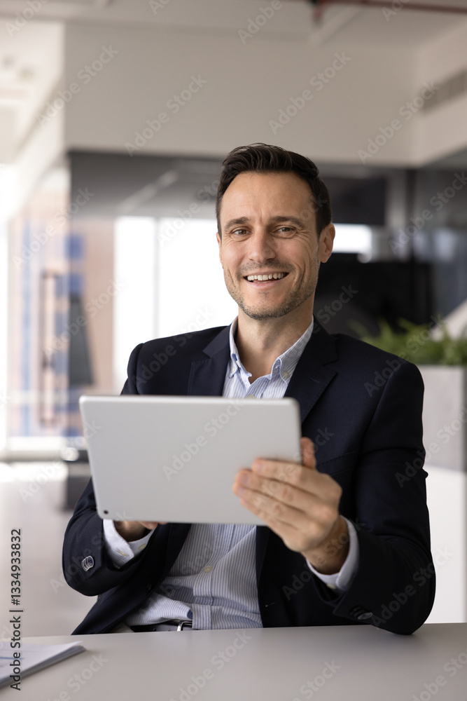 Happy confident business professional man using application, modern online web technology on tablet for work management, financial transactions, trading, looking at camera, smiling for portrait