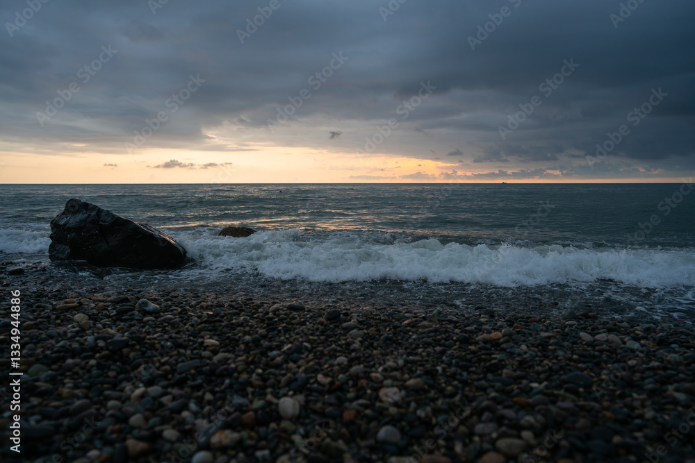 Obraz premium Sunset on a rocky sea beach with clouds