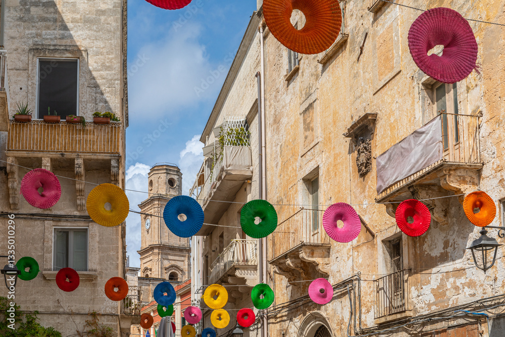 Via Giuseppe Garibaldi, magnifiquement décorée avec des cercles colorés suspendus, avec le clocher de la Chiesa di San Francesco d'Assisi en arrière-plan, à Monopoli, dans les Pouilles, Italie