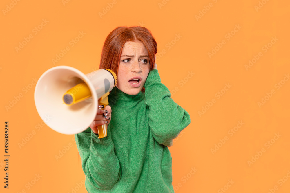 Woman in green sweater holding a megaphone while expressing surprise against bright orange background during a lively event Woman in green sweater holding a megaphone while expressing surprise against bright orange background during a lively event