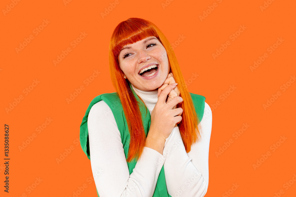 Brightly smiling woman with orange hair and green outfit expressing joy against a vibrant orange background during a playful photoshoot Brightly smiling woman with orange hair and green outfit expressing joy against a vibrant orange background during a playful photoshoot
