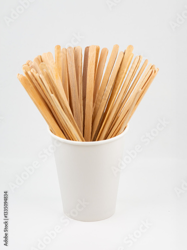 Wooden sticks for stirring a coffee drink in a disposable cup.