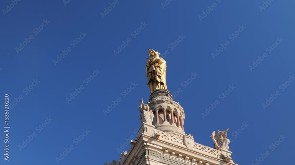 The golden Madonna and Child statue atop Notre-Dame de la Garde in Marseille stands against a clear blue sky. A low-angle shot highlights the intricate details of this religious landmark. The golden Madonna and Child statue atop Notre-Dame de la Garde in Marseille stands against a clear blue sky. A low-angle shot highlights the intricate details of this religious landmark.