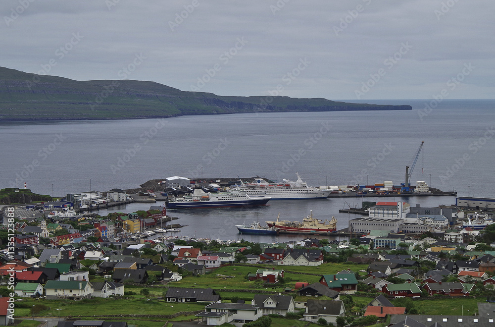Classic expedition cruiseship cruise ship liner Delphin docked at pier in Thorshavn, Faroe Islands with cliffs and fjord landscape in background and city skyline during Arctic Circle summer cruising