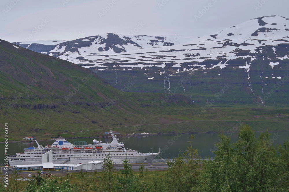 Classic expedition cruiseship cruise ship liner Delphin docked at pier in Seydisfjördur, Iceland with harbor skyline and fjord landscape in background on during Arctic Circle summer cruising