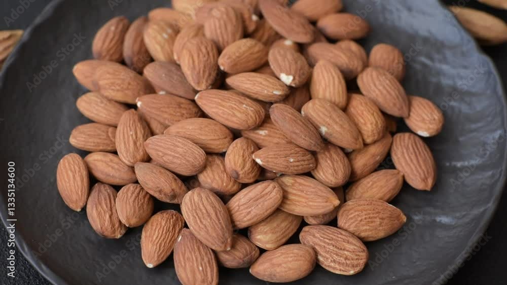 Roasted or raw peeled almonds in bowl on dark concrete background