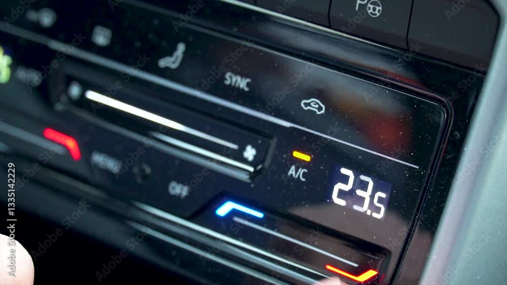 A person adjusts the temperature on the car's climate control. A person adjusts the temperature on the car's climate control.