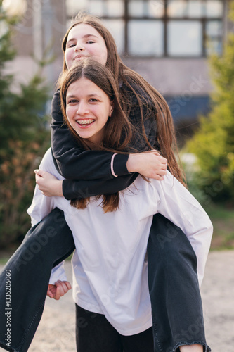 Happy girls enjoying a piggyback ride, celebrating youth and connection outdoors