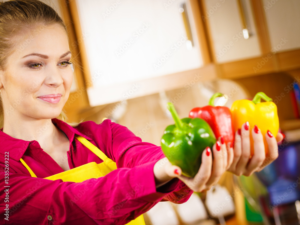 Happy woman holding bell peppers paprika