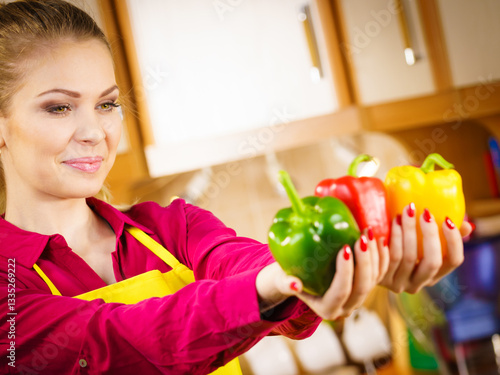Happy woman holding bell peppers paprika