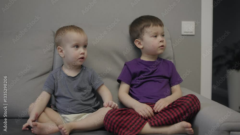 Two young brothers seated on sofa faces dotted with red dots of chickenpox. Boys with illness red dots on faces clear indication of their struggle with chickenpox discomfort with red spots on faces Two young brothers seated on sofa faces dotted with red dots of chickenpox. Boys with illness red dots on faces clear indication of their struggle with chickenpox discomfort with red spots on faces