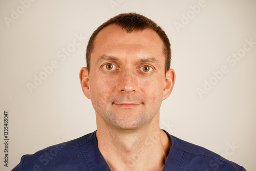 In dark blue medical clothing, the man poses for a detailed photo. His focused gaze radiates professionalism and authority. The image emphasizes care, commitment, and expertise.