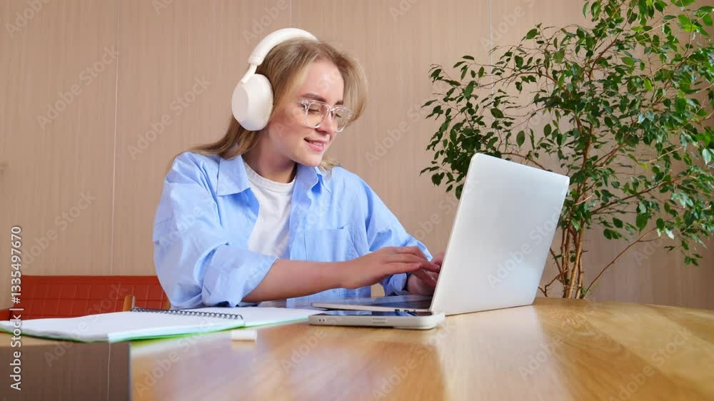Smiling woman participates in a video call, using a laptop in a bright, stylish workspace. Smiling woman participates in a video call, using a laptop in a bright, stylish workspace.