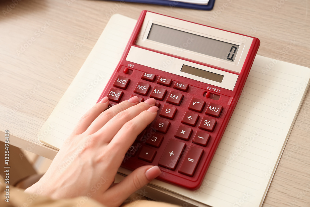 Female accountant with calculator and notebook at table in office Female accountant with calculator and notebook at table in office