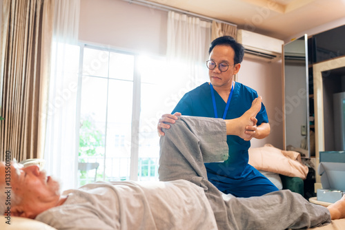 фотографія Asian senior man patient doing rehab physical therapy stretching muscle leg and knee with physiotherapist caregiver on bed in bedroom