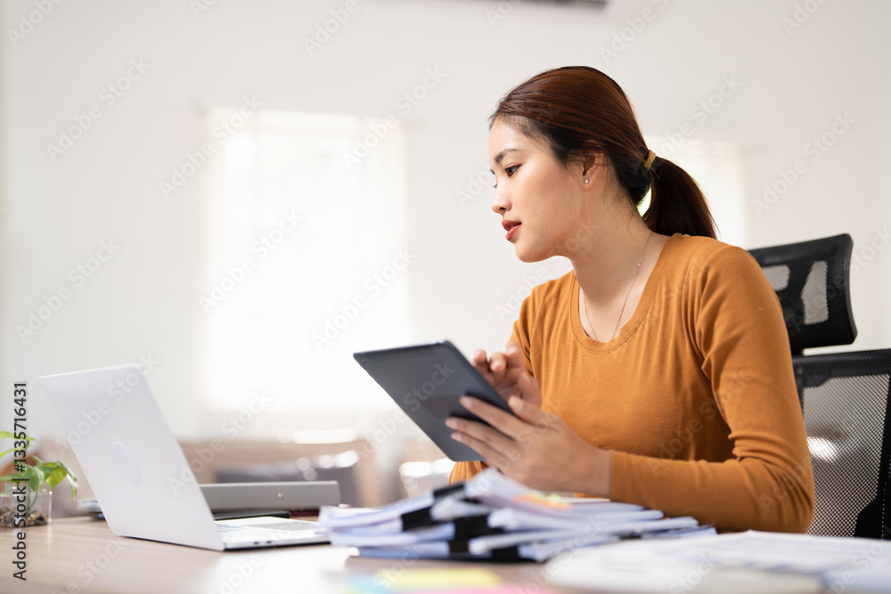 Successful businesswoman using digital tablet and laptop working online sitting in home office. Professional businesswoman looking at computer screen distantly working from home. Successful businesswoman using digital tablet and laptop working online sitting in home office. Professional businesswoman looking at computer screen distantly working from home.