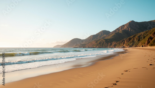 Beach with gentle waves and mountains at sunset