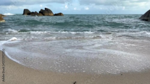 waves on the beach, view of a sandy beach with a gentle ocean wave washing ashore. The soft foam contrasts with the fine sand, peaceful coastal scene, smooth sand in the foreground, gentle ocean wave