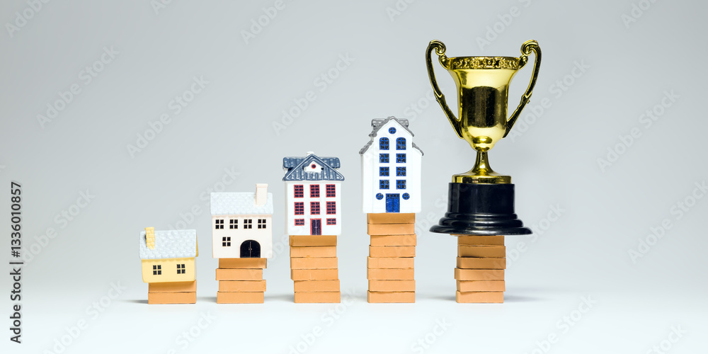 Miniature houses stacked on bricks with a trophy symbolize growth in real estate investments, increased property value and financial success.