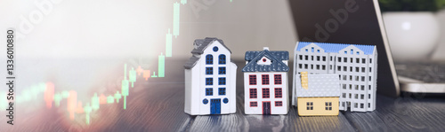 Obraz na płótnie Miniature houses with stock market chart and laptop, symbolizing real estate investment, property market trends, and financial growth opportunities. w salonie