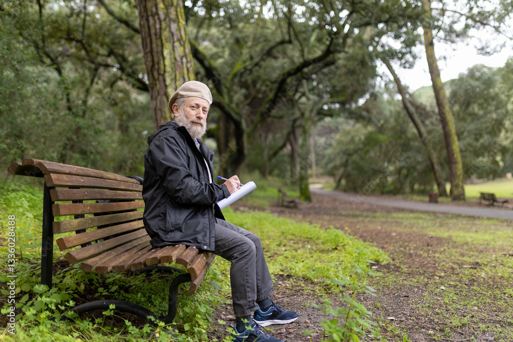 Senior writer taking notes in peaceful park setting Senior writer taking notes in peaceful park setting