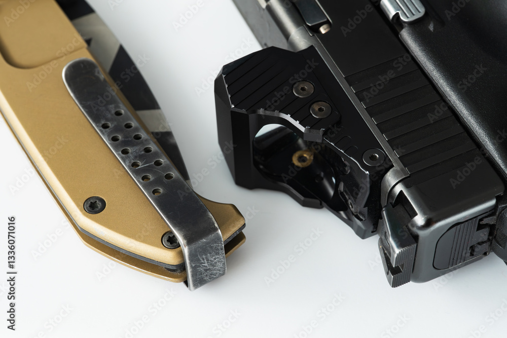 Modern red dot sight on a pistol and tactical folding knife, macro photo. Modern red dot sight on a pistol and tactical folding knife, macro photo.