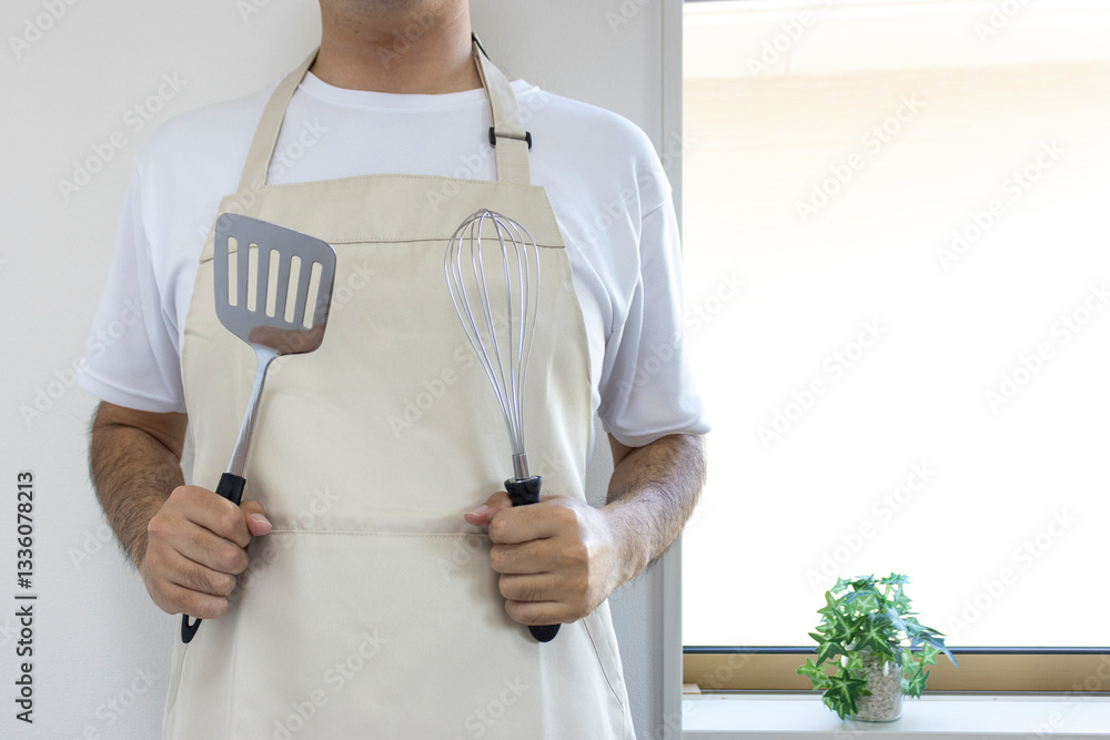 エプロンを付け料理道具を持つ男性(顔無し、日本人、30代)