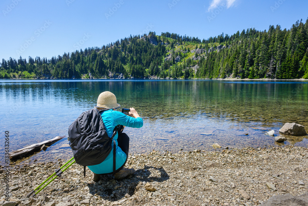 Woman taking photos of Summit Lake using a smartphone. Mt Rainier National Park. Washington State.