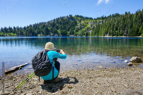 Obraz na płótnie Woman taking photos of Summit Lake using a smartphone. Mt Rainier National Park. Washington State. w salonie
