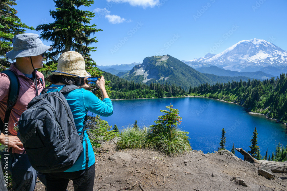 Couple taking photos of Summit Lake using a smartphone. Mt Rainier in the distance. Mt Rainier National Park. Washington State.