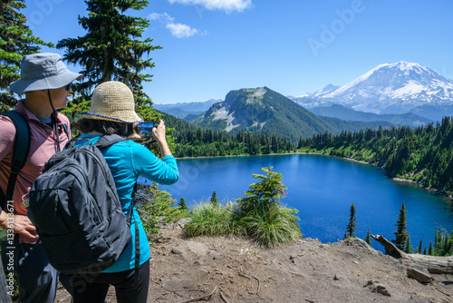 Obraz na płótnie Couple taking photos of Summit Lake using a smartphone. Mt Rainier in the distance. Mt Rainier National Park. Washington State. w salonie