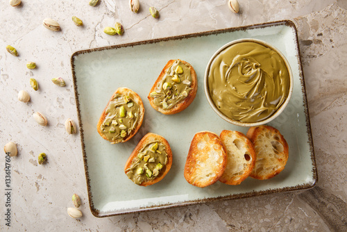 Obraz na płótnie Vegetarian Pistachio cream, toasted bread and raw nuts close-up on table. Horizontal top view from above w salonie