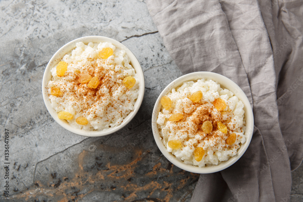 Bowl of tasty rice pudding with cinnamon, vanilla and raisins closeup on the table. Horizontal top view from above