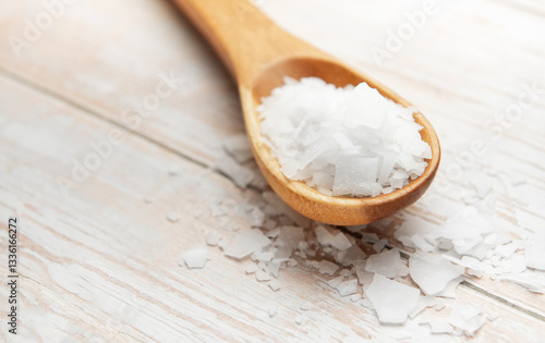 Photos Wooden spoon holding magnesium chloride flakes on white table
