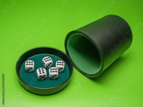 close up of five  white dice showing  six  in cup lid against a green background