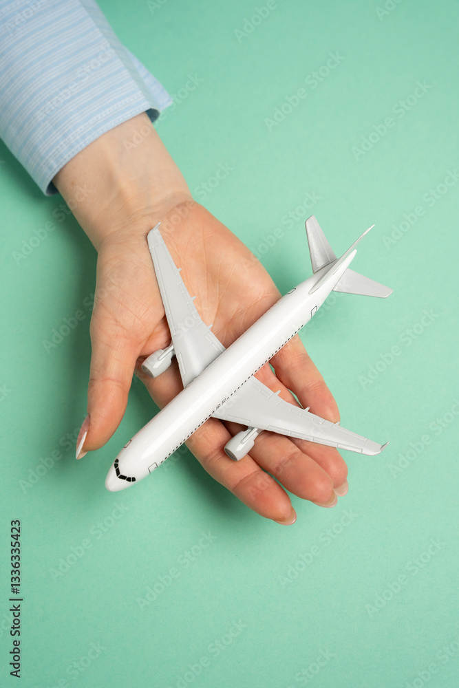 An airline passenger plane in the palm of a woman's hand. Flight ticket booking concept. Flight reservations, travel planning, vacation preparations. Airline ticket sales, booking services, tourism