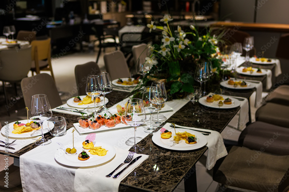 Fototapeta premium Luxurious dining table setup featuring gourmet appetizers, elegant glassware, floral centerpiece