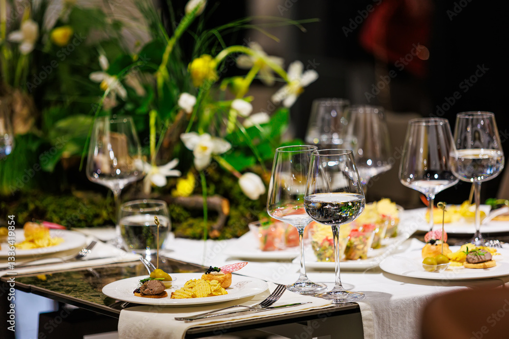 Luxurious dining table setup featuring gourmet appetizers, elegant glassware, floral centerpiece Luxurious dining table setup featuring gourmet appetizers, elegant glassware, floral centerpiece