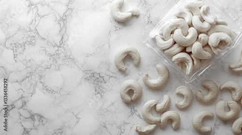 Overhead view of cashews on a marble surface with a container