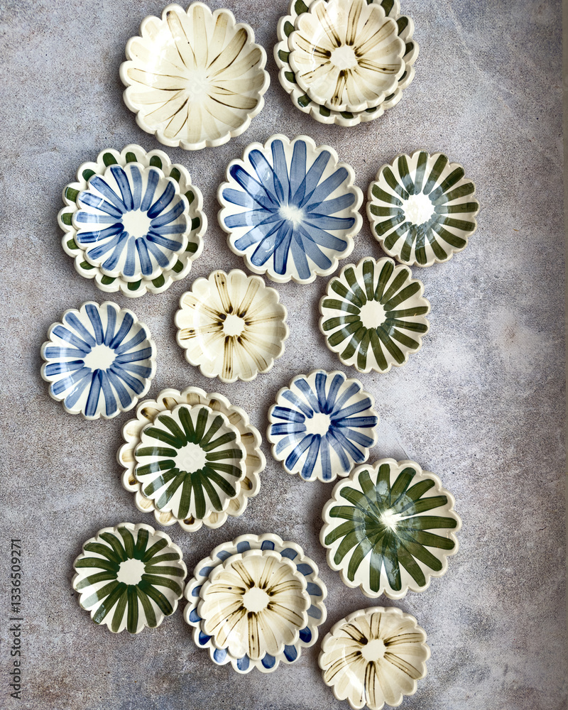A selection of handmade stoneware ceramics in various glazes and decorations on warm stone background