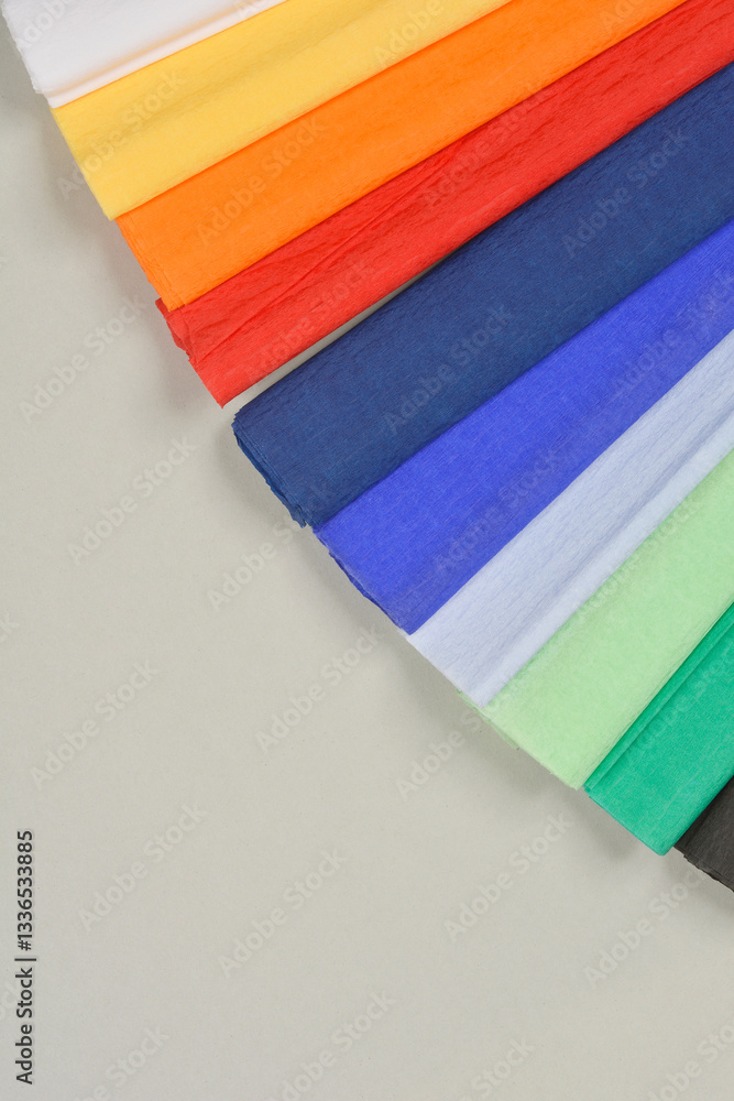 Obraz premium A close-up, angled shot of colorful crepe paper sheets arranged in a diagonal pattern, showcasing their vibrant hues and delicate texture against a neutral background