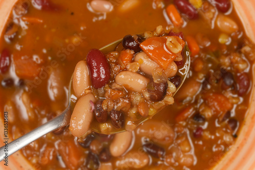 Фотография A close-up, top-down shot of a spoonful of bean stew, showcasing the variety of