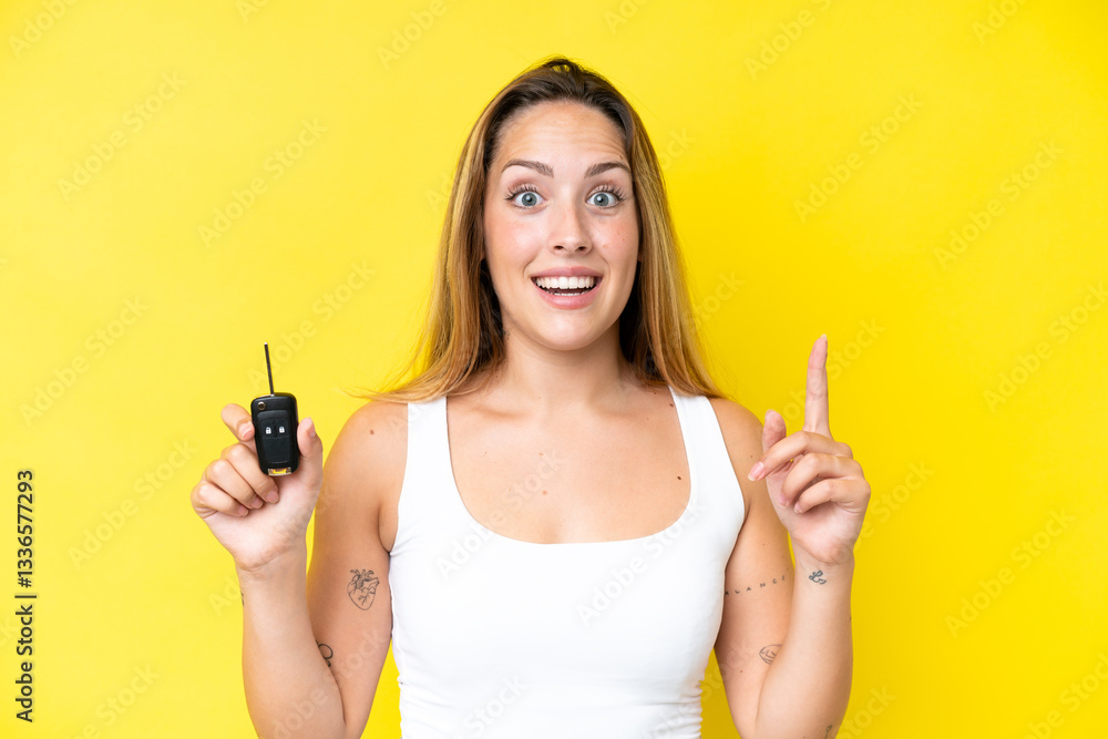 Young caucasian woman holding car keys isolated on yellow background pointing up a great idea Young caucasian woman holding car keys isolated on yellow background pointing up a great idea