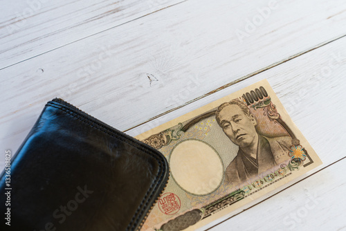 旧一万円札と黒い財布、白い木目調テーブル