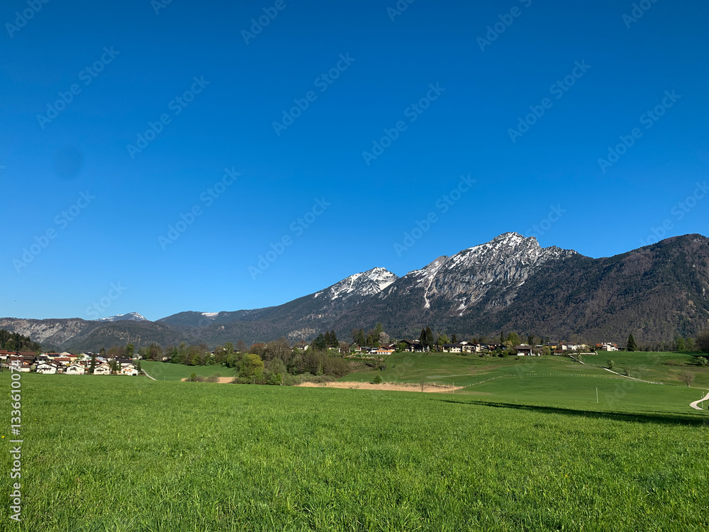 Obraz premium Wide green meadow with a small village in the foreground