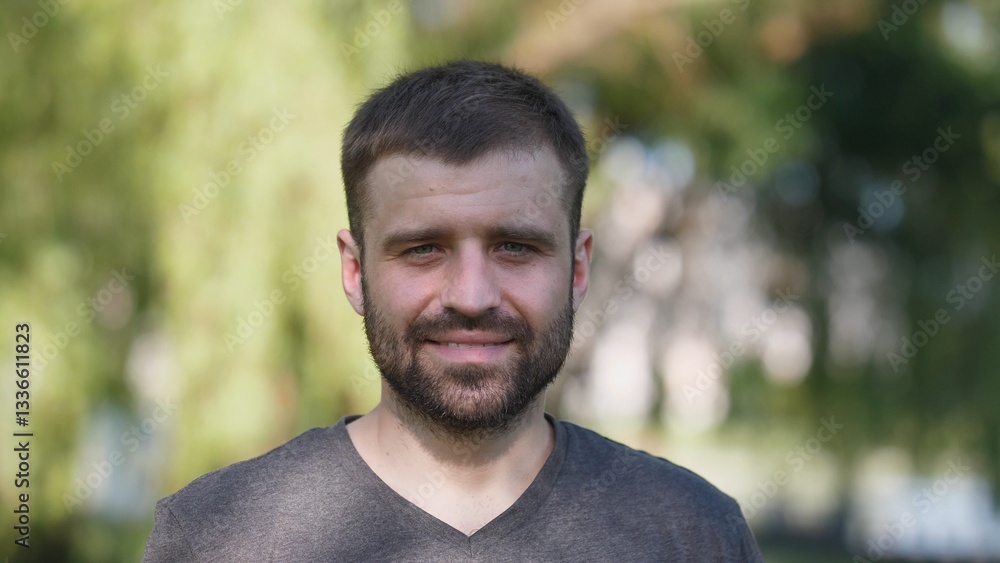 A cheerful man is posing outdoors against a backdrop of lush greenery and warm natural light all around A cheerful man is posing outdoors against a backdrop of lush greenery and warm natural light all around
