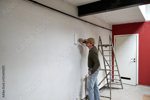 Painter in dirty clothes renovate a wall in a loft