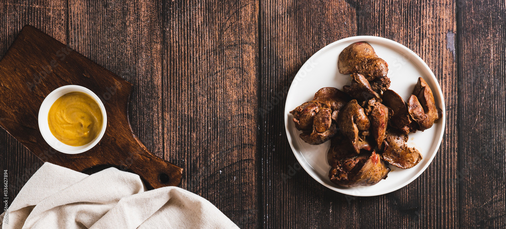 Homemade stewed chicken liver on a plate on the table top view web banner