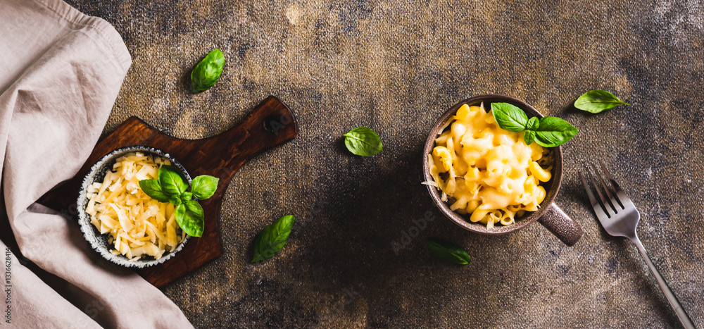 Cup with baked macaroni cheese and basil on the table top view web banner